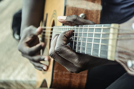 person holding brown and black dreadnought acoustic guitar