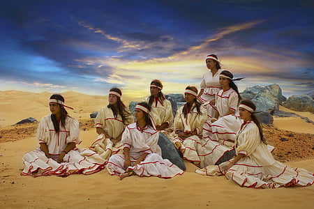 group of women wearing white dress sitting on brown sand