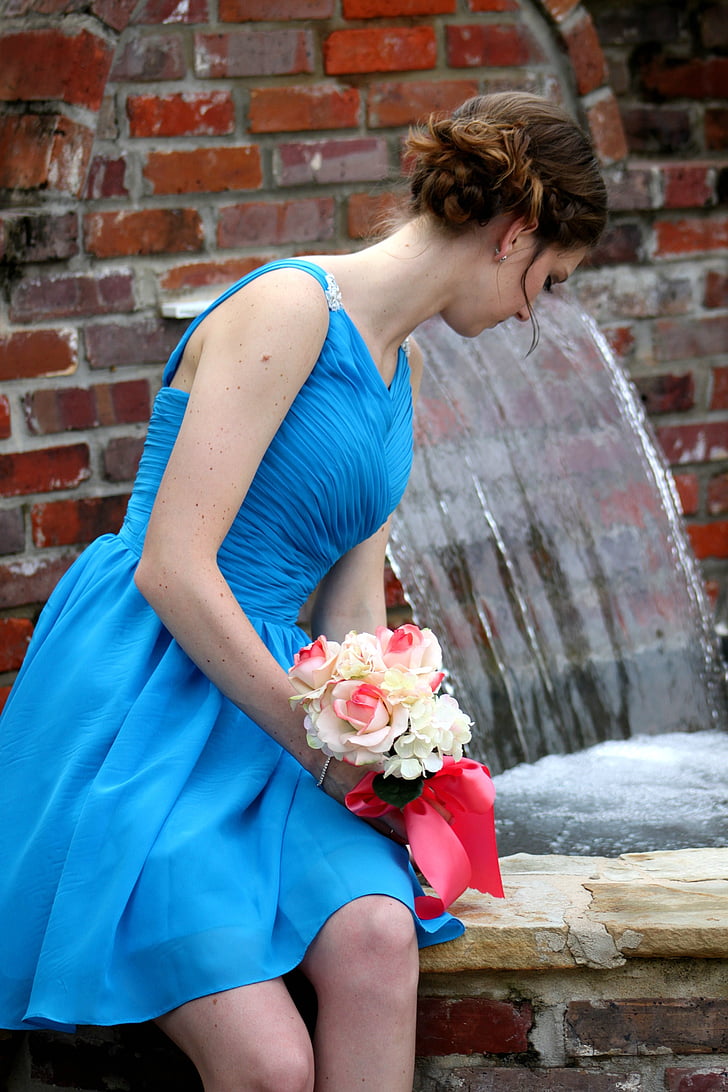 woman in blue spaghetti strap dress holding bouquet of flowers
