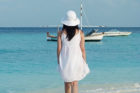 woman wearing white spaghetti strap dress standing by the beach