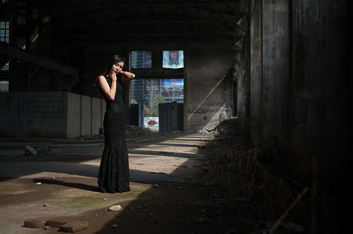 standing woman with black sleeveless dress inside building