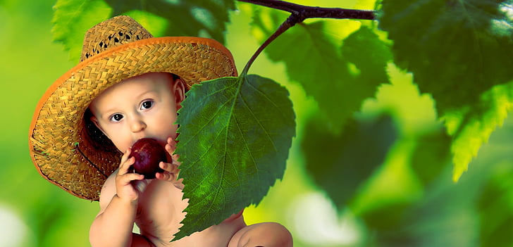 baby wearing straw hat eating fruit