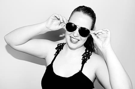 grayscale photo of smiling woman wearing camisole and sunglasses