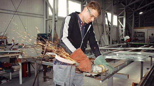 man welding metal frame during daytime