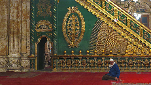 man sitting on red floor beside green and yellow wall