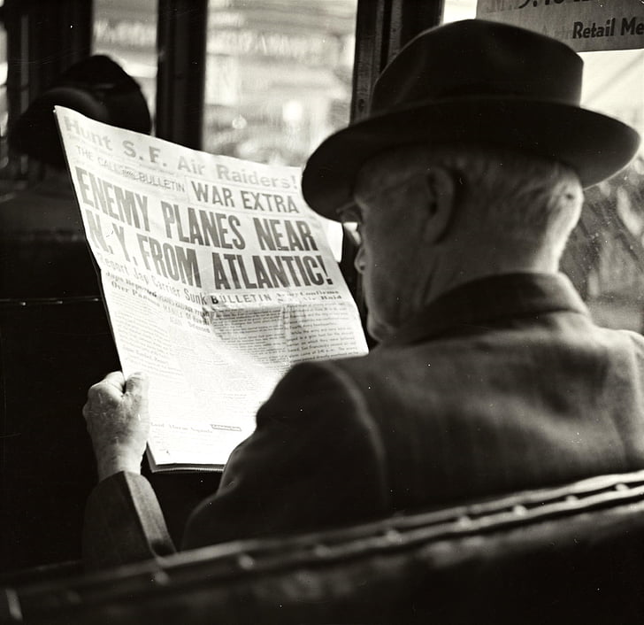 grayscale photography of man reading newspaper