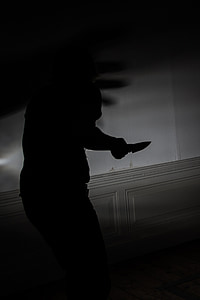 photograph of silhouette person holding a knife