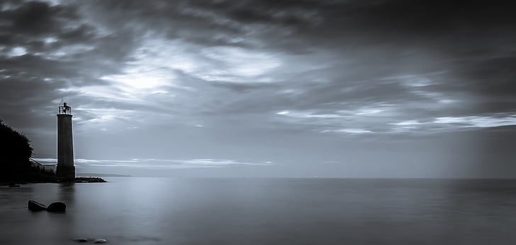 greyscale photography of lighthouse near ocean