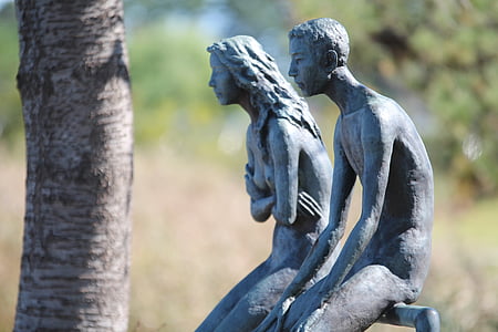 man and woman sitting on rail statues