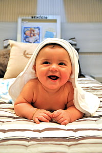 baby lying on brown and white stripe comforter while smiling