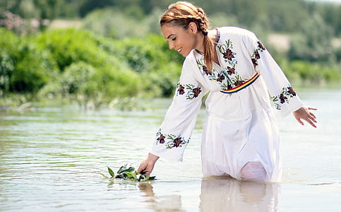 woman with white and brown floral dress in body of water at daytime