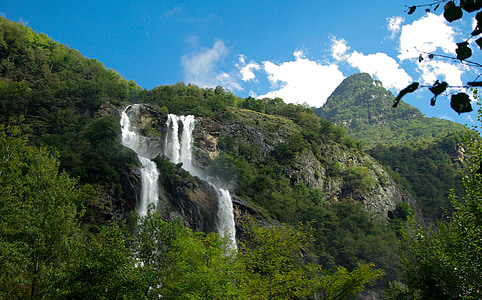 waterfalls near tree under white and blue sky during daytime photography