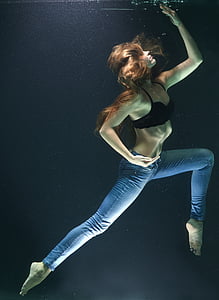 woman wearing black brassiere and blue fitted jeans submerged in water