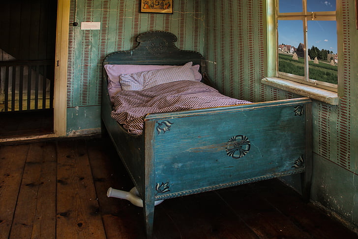 closeup photo of teal bed with pink bed sheet near window