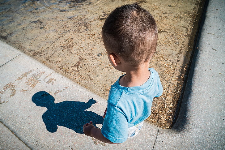 boy looking at shadow on sidewalk