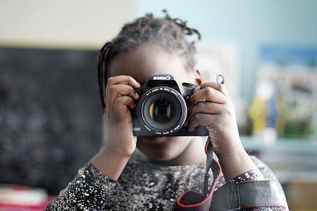 tilt shift lens photography of girl holding black Canon DSLR camera
