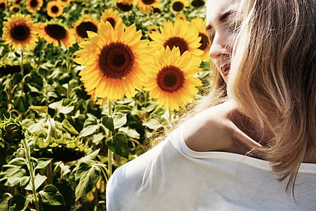 photo of woman in white top beside sunflowers