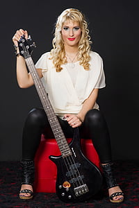 woman holding black 4-stringed electric bass guitar