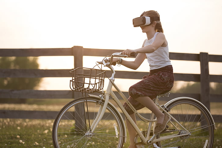 photograph of girl ride on female beach cruiser bike with VR headset