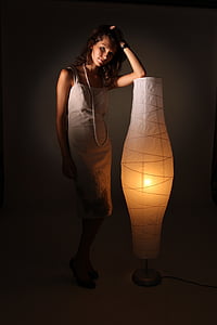 woman wearing grey spaghetti-strap dress standing with paper rice floor lamp