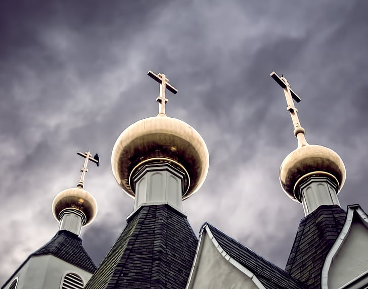 low angle photography of three gray towers with crosses under cloudy sky