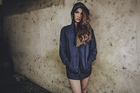 woman wears blue zip-up pullover hoodie near gray concrete wall
