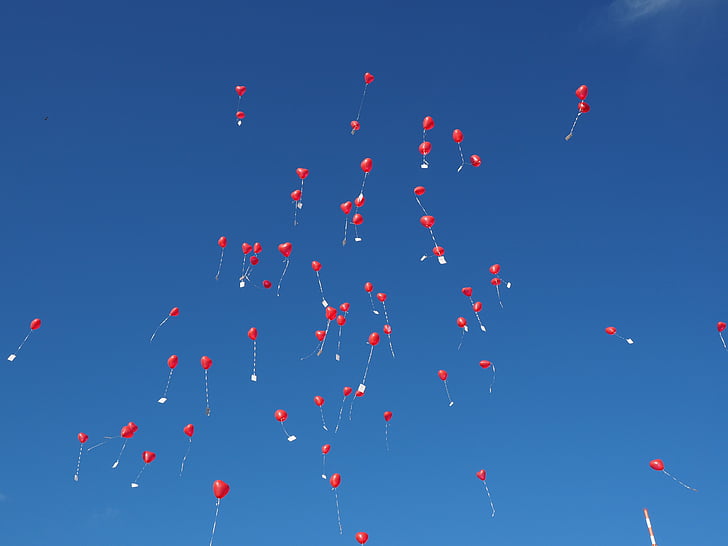 red balloons flying under clear blue sky during daytime