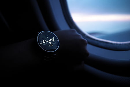 person wears black and grey smartwatch while riding airplane