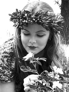 grayscale photo of woman smelling flower