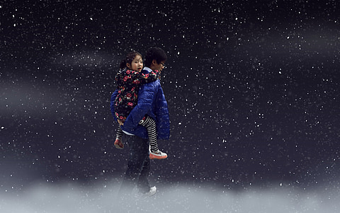 person wearing blue jacket carrying girl wearing black and pink jacket on star background