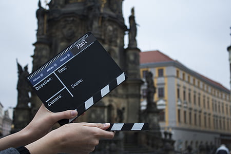person holding black and white clapperboard outdoors