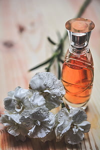 white flowers beside clear glass spray bottle on brown wooden desk