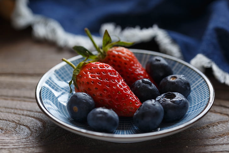 two red strawberries on blue ceramic saucer
