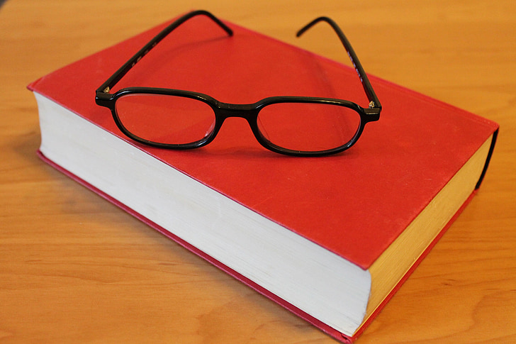 black framed eyeglasses on red closed book
