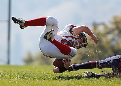 depth of field photography of american football athlete about to fall on ground
