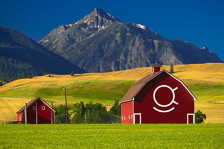 two red wooden houses near mountain under blue sky at daytime