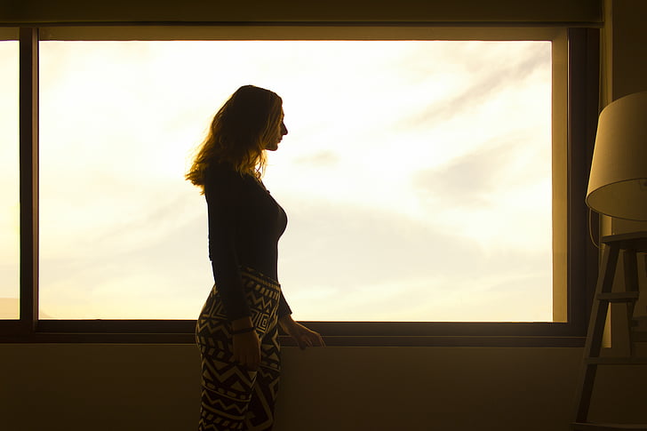 silhouette of woman near window pane