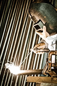 person wearing gray welding mask welding a steel bar