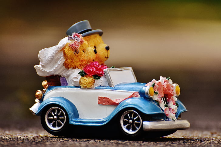 selective focus photography of bride and groom bear riding car figurine