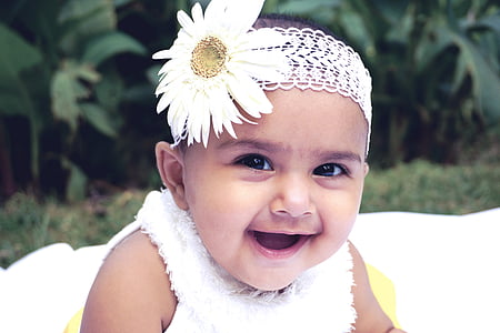 baby in white fleece sleeveless shirt wearing white daisy flower head accessory