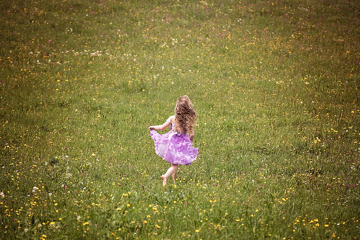 girl in purple dress standing on green grass field
