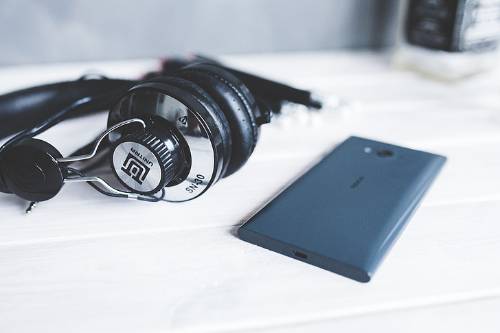 gray and black headphones beside blue Android smartphone