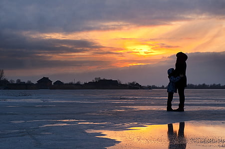 adult and toddler on seashore during golden hour