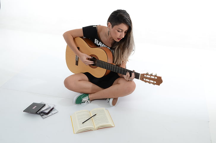 woman playing guitar inside white painted room