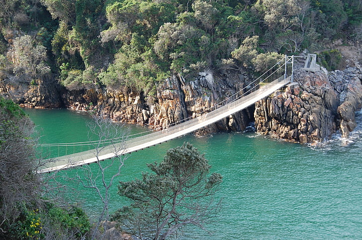 brown wooden bridge connecting gray stony islands