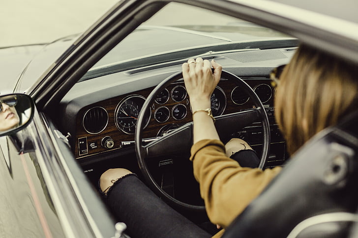 person sits and holds vehicle steering wheel