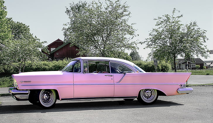 classic pink coupe on road near trees during daytime