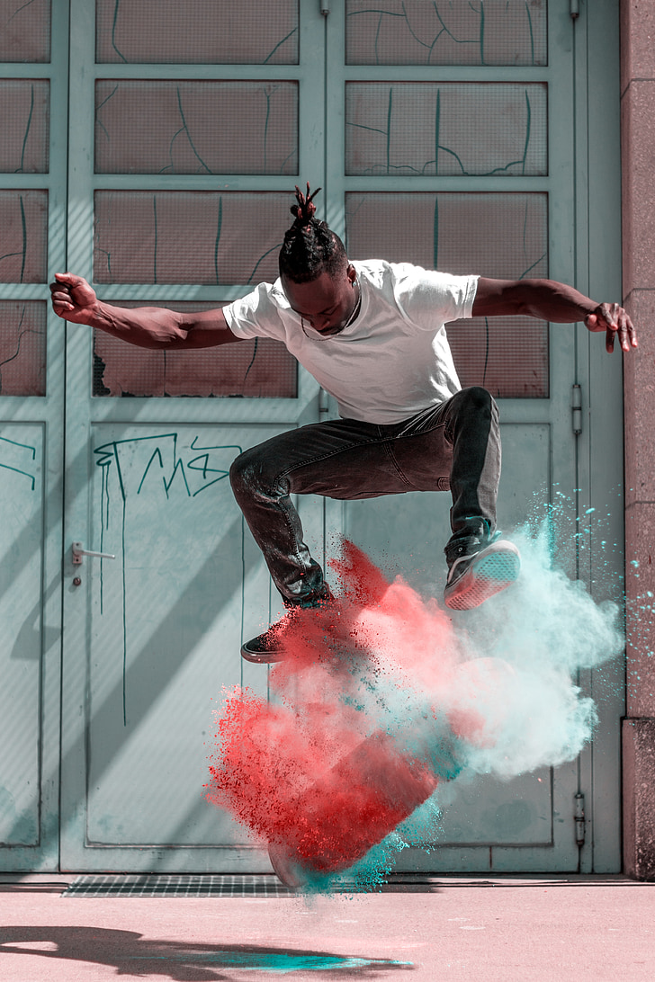man doing skateboard stunts with blue and orange powder