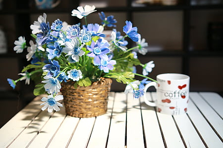 white and red coffee-printed ceramic mug near flower decor