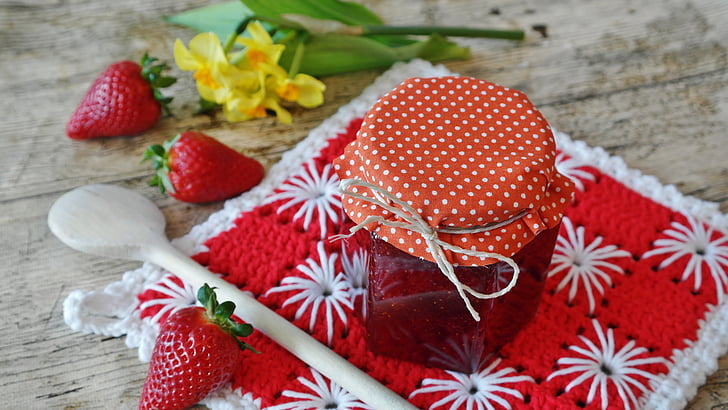 strawberry jam in clear bottle with three strawberry fruits beside
